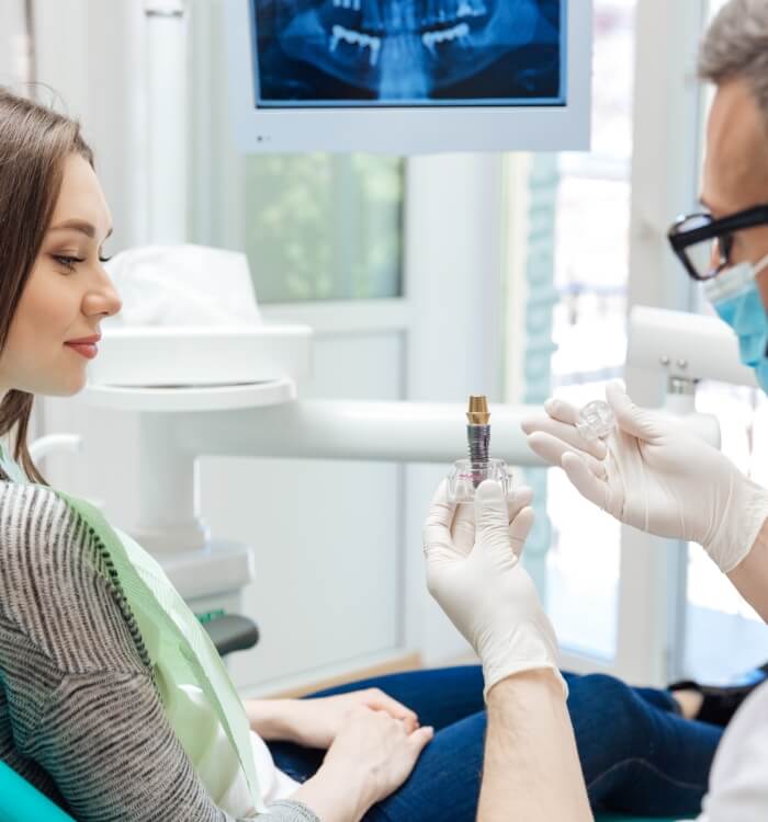 Dentist using dental implant model to explain the four step dental implant process