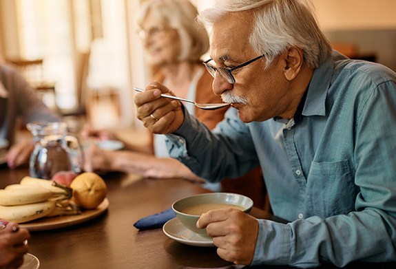 A man, eating soup after dental implant surgery