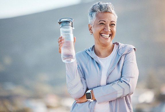 Woman smiling with water bottle on hike outside
