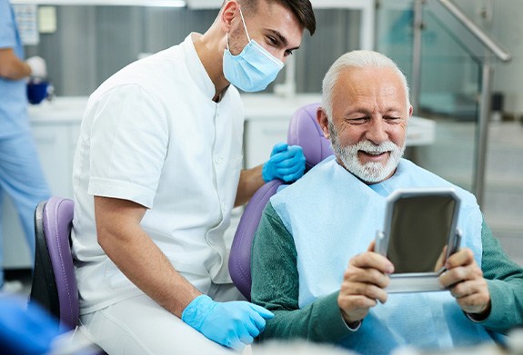 Patient looking at reflection in mirror with dentist