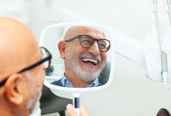 A man looking at his newly restored smile after dental implant surgery