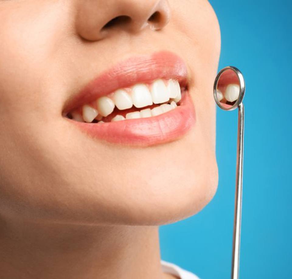 Dental mirror being raised next to patient’s smile