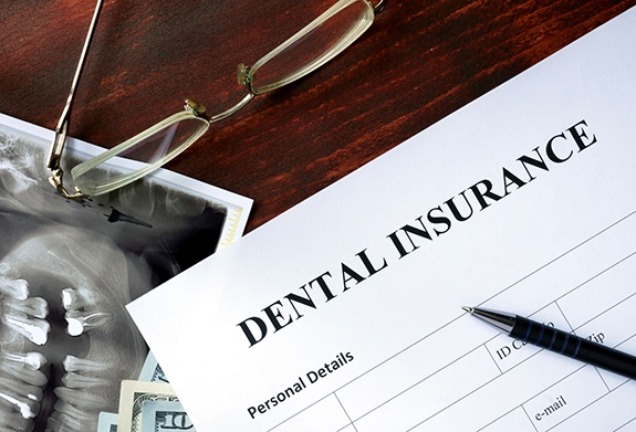 Top of dental insurance form with pen and glasses