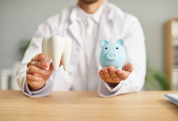 Dentist holding blue piggy bank and large model tooth