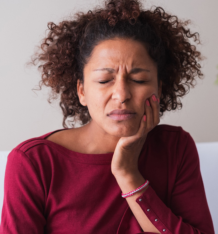 Woman grabbing cheek due to tooth pain