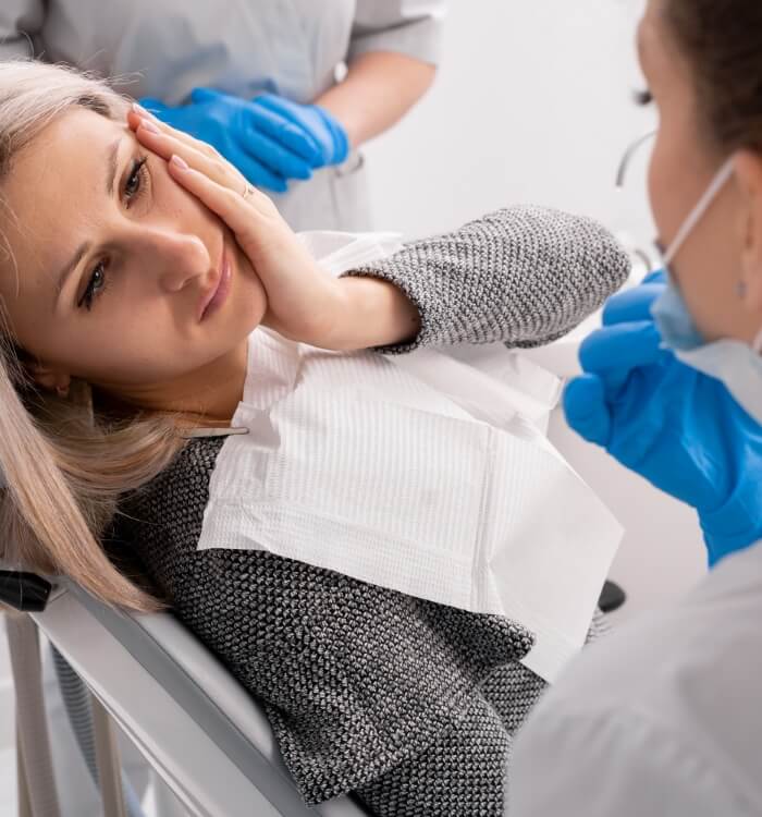 Woman holding cheek in pain before emergency dentistry