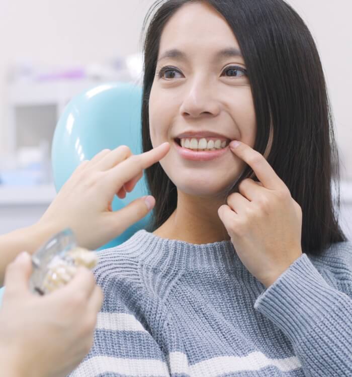 Woman pointing to smile and enjoying the benefits of dental implants