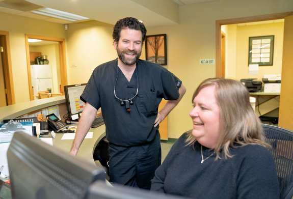 Montpelier dentist and dental team member behind dental office reception desk