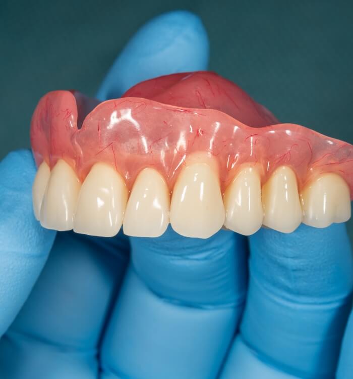 Hand holding a full arch denture