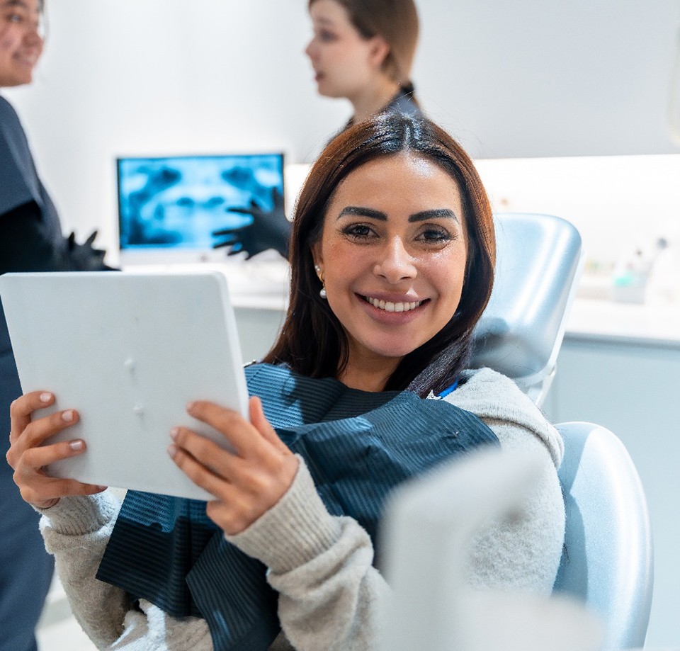 Patient smiling while holding mirror in treatment chair