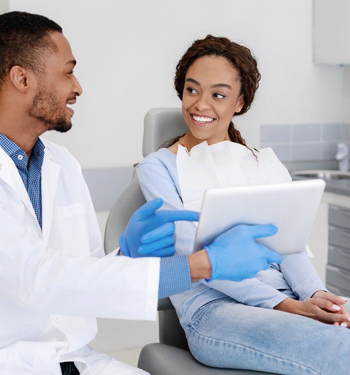 Dentist and patient smiling at each other in dental office