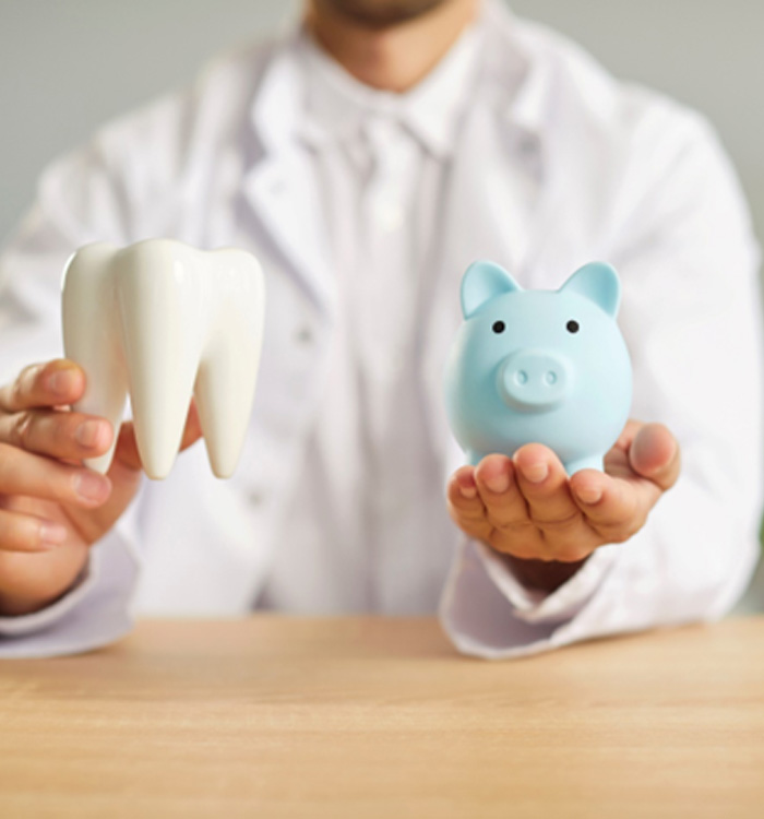 Man holding model tooth and blue piggy bank