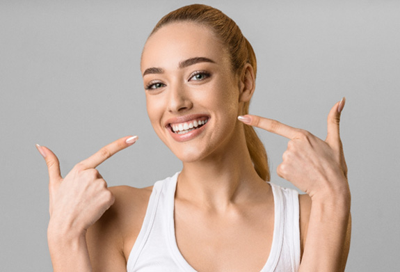 Woman pointing to her smile with both hands