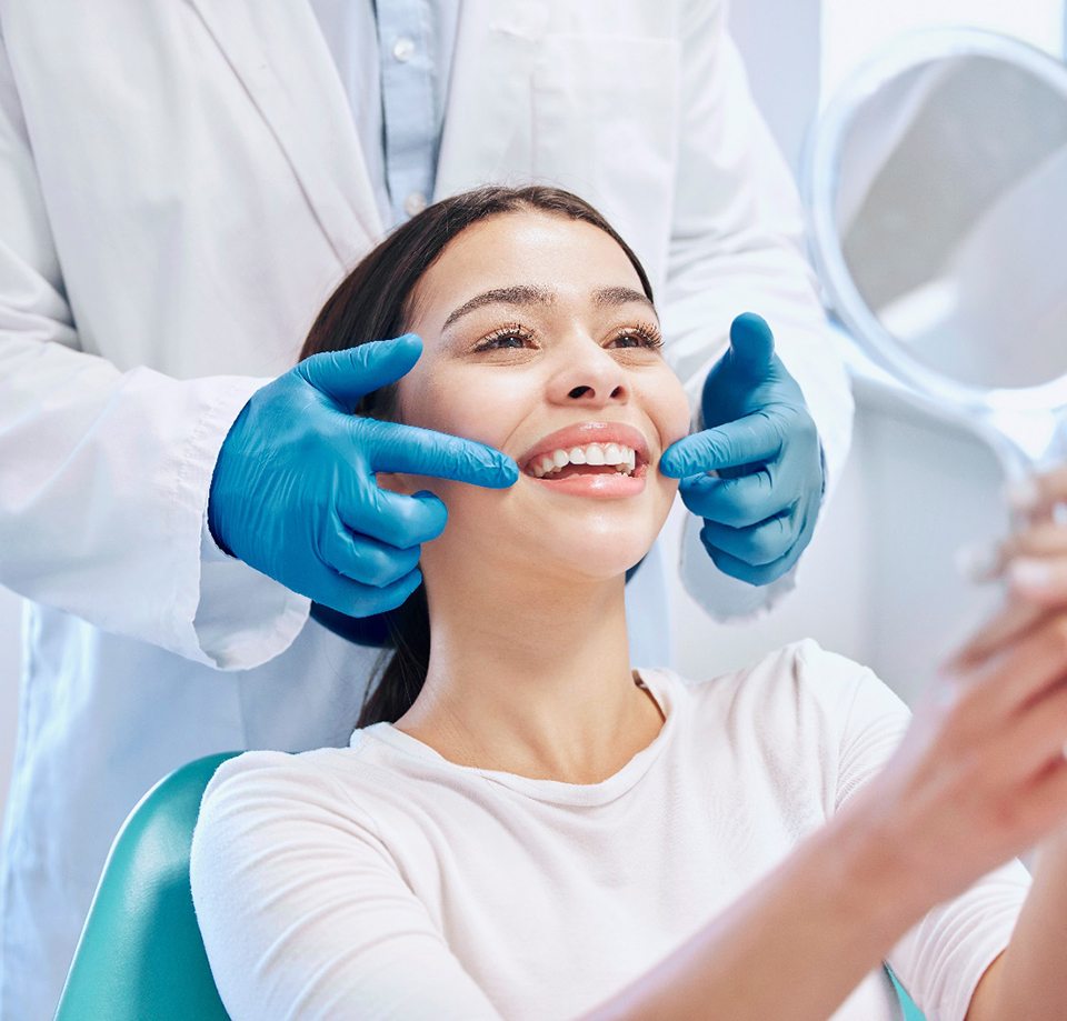 Dentist touching patient’s smile with two blue-gloved hands