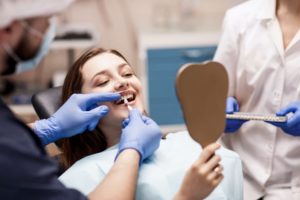 a cosmetic dentist holding a shade chart up to a patient's mouth